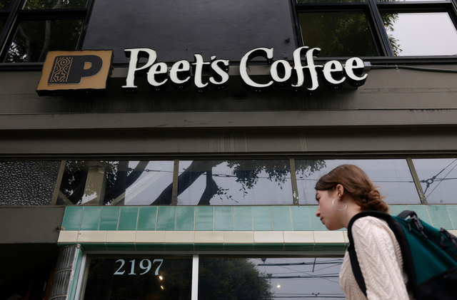 A Peet’s Coffee storefront displays the name and address “2197" while a woman with a backpack walks past it.